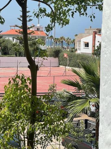 a view of a tennis court with trees and buildings at Appartement pieds dans l’eau à sidi Rahal in Sidi Rahal