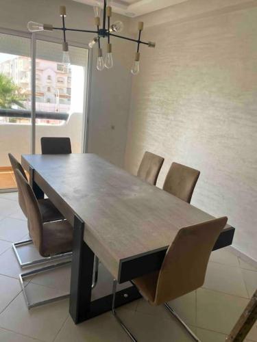 a dining room table with chairs and a wooden tableablish at Appartement pieds dans l’eau à sidi Rahal in Sidi Rahal