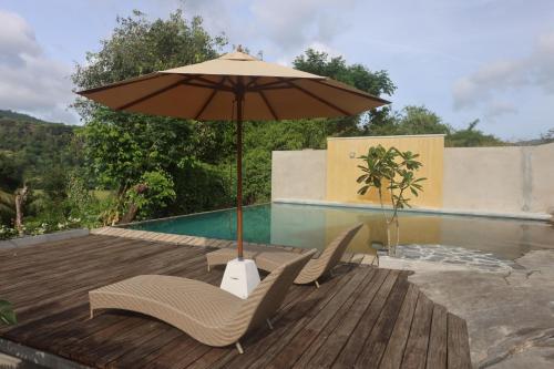 two chairs and an umbrella on a deck next to a pool at Stone Cottage in Kandy