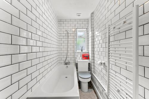 a white bathroom with a tub and a toilet at Stunning Norwich Gem Sleeps 7 - Parking - Garden in Earlham