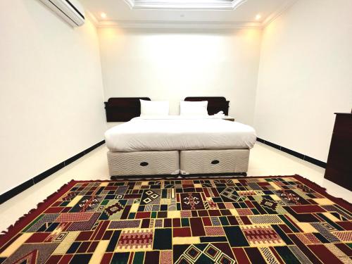 Al Taraf Hotel Apartment في صور: غرفة نوم مع سرير وسجادة على الأرض