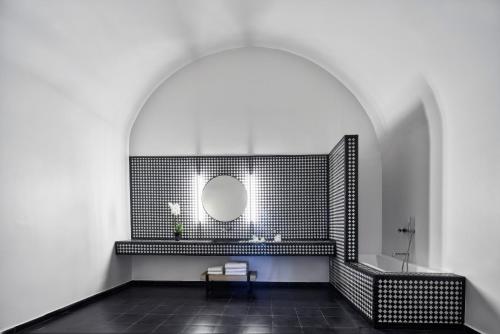 a bathroom with a mirror and a black tiled wall at Katikies Garden Santorini - The Leading Hotels Of The World in Fira