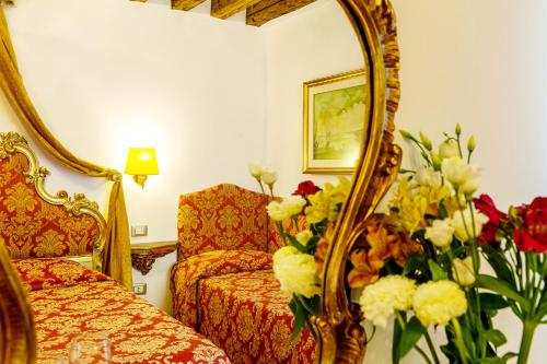 a hotel room with a mirror and a couch and flowers at Hotel Al Vagon in Venice