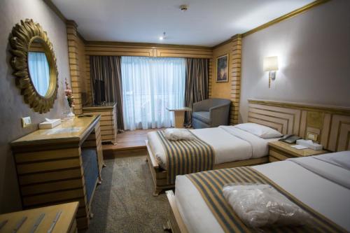a hotel room with two beds and a desk and a mirror at ToBadaa - Nile cruise all inclusive from Aswan or Luxor 4 Days & 7 days in Aswan