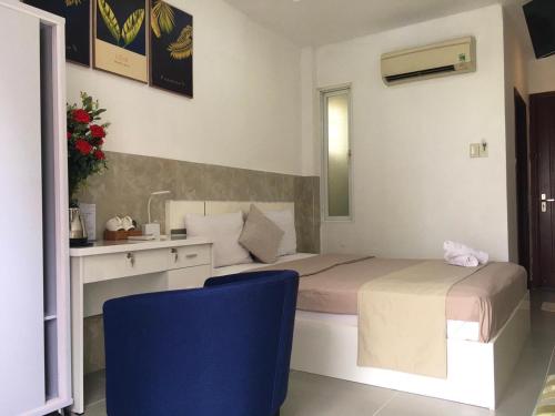 een slaapkamer met een bed, een bureau en een blauwe stoel bij SaiGon CoZy Hotel "241 Pham Ngu Lao Street'' in Ho Chi Minh-stad