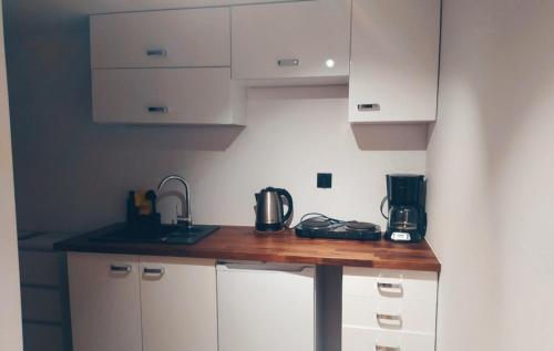 a kitchen with white cabinets and a wooden counter top at Apartamenty w Pieninach in Sromowce Wyżne