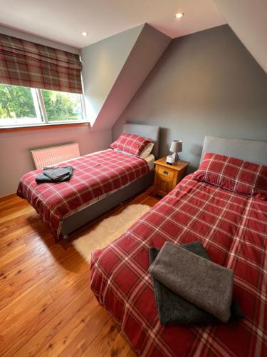 two beds in a room with two windows at Barty’s Bothy in Contin