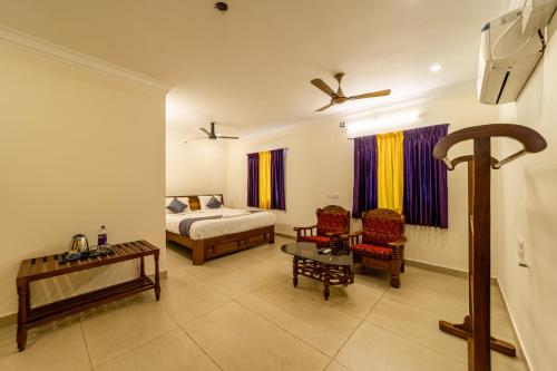 a bedroom with a bed and chairs and a table at Yellow Residency in Puducherry