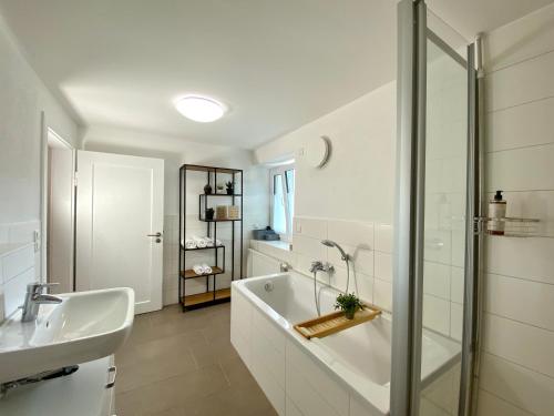 a white bathroom with a tub and a sink at Modernes 3-Familienhaus im Allgäu in Erkheim