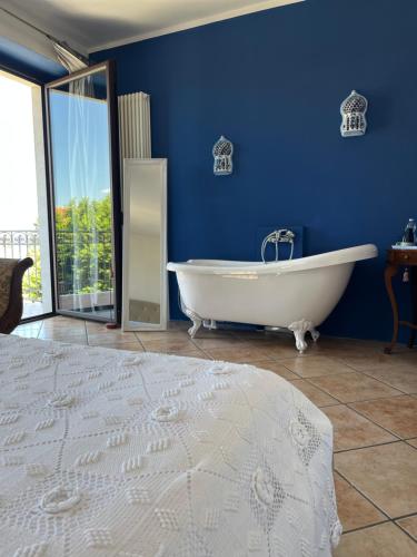 ein blaues Bad mit einer weißen Badewanne und einem Bett in der Unterkunft The Tower Of The Old King in Desenzano del Garda