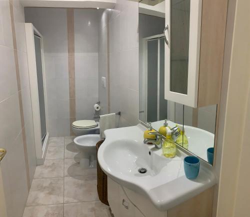 La salle de bains blanche est pourvue d'un lavabo et de toilettes. dans l'établissement Villa Ale., à Pulsano
