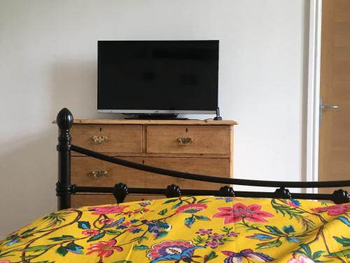 un televisor sentado en la parte superior de un tocador con una cama en 2 Double Rooms-Sleeps 4- 2 Bathrooms en Rossendale