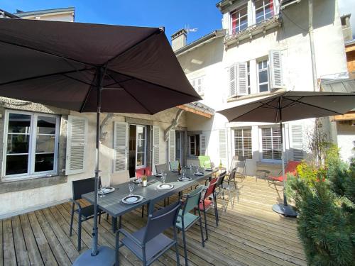 夏蒙尼-勃朗峰莱昂别墅的木甲板配有桌子和两把遮阳伞