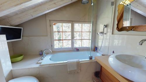 La salle de bains est pourvue d'une baignoire, d'un lavabo et d'une fenêtre. dans l'établissement Chalet Zeppelin, à Château-d'Oex