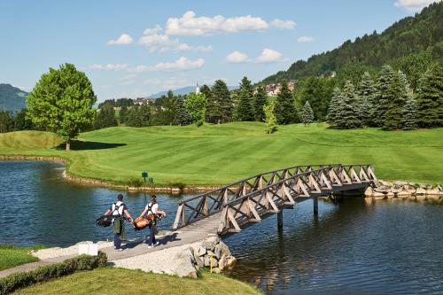 two people walking over a bridge over a river at Luxury Chalets Gradenbach near Schladming in Haus im Ennstal
