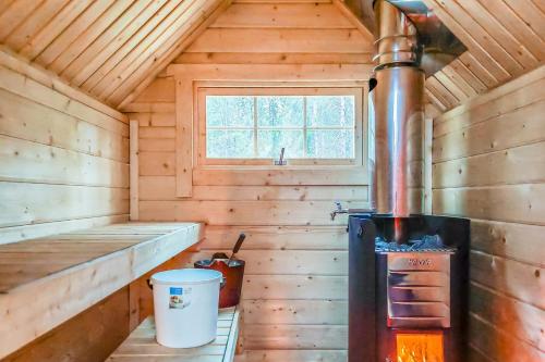 uma cabana de madeira com um fogão e uma janela em Karhunkierros Cabins & Huts em Salla