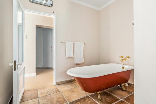 La salle de bains est pourvue d'une baignoire rouge. dans l'établissement Garden Oasis, à Knysna
