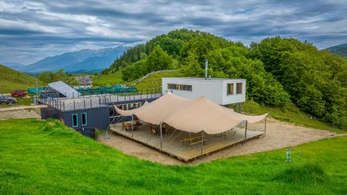 ein Gebäude mit einem Zelt in der Mitte eines Feldes in der Unterkunft Ursa Mica Glamping Resort in Şirnea