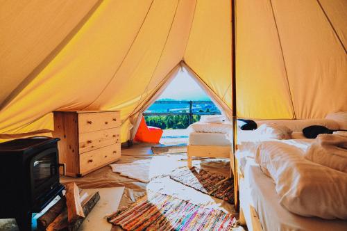 Ursa Mica Glamping Resort في سيرنيا: خيمة فيها سريرين وموقد