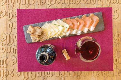 a plate of cheese and a glass of wine on a table at Alpenhotel Wanderniki in Liesing