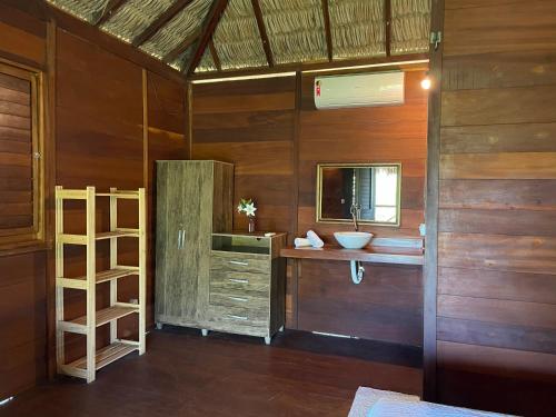 Habitación con baño con paredes de madera y lavabo. en Atins Bangalôs, en Atins