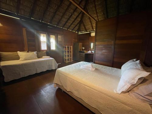twee bedden in een kamer met houten wanden bij Atins Bangalôs in Atins