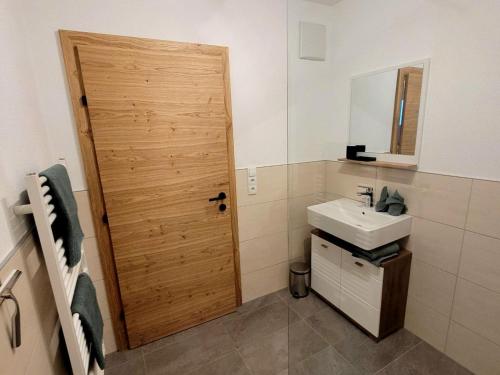 a bathroom with a sink and a wooden door at New apartment in the beautiful Pitztal in Oberlehn