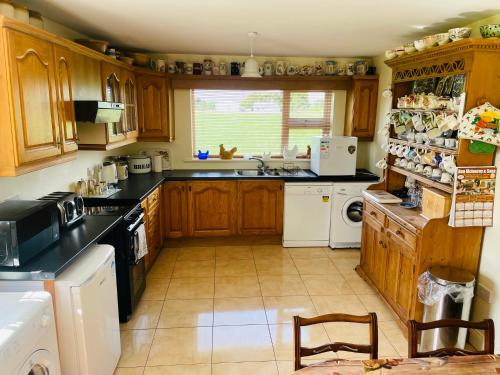 una cocina con armarios de madera y encimeras negras en Cutteen Cottage, en Tulla