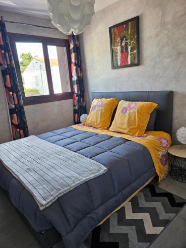 - une chambre avec un lit doté de draps bleus et d'oreillers jaunes dans l'établissement Appartement de charme , Royan, proche mer avec balcon., à Royan