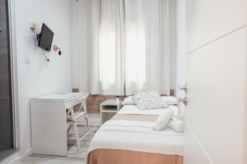 a small white room with a bed and a desk at Hostal Ruta de Francia in Barcelona