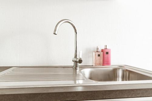 a stainless steel kitchen sink with a pink bottle on it at Luxe studio in Ostend