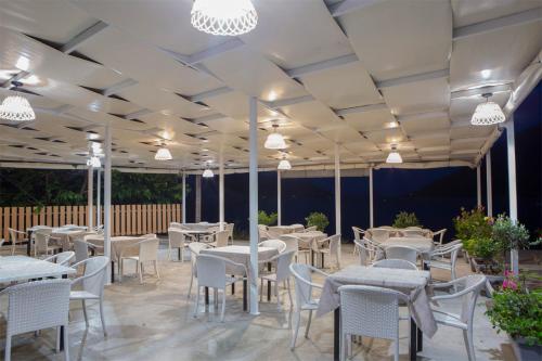 een restaurant met witte tafels, stoelen en verlichting bij Menes Hotel in Yénion