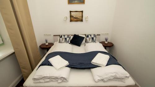 een slaapkamer met een bed met witte lakens en kussens bij Kira Panzió in Lengyeltóti