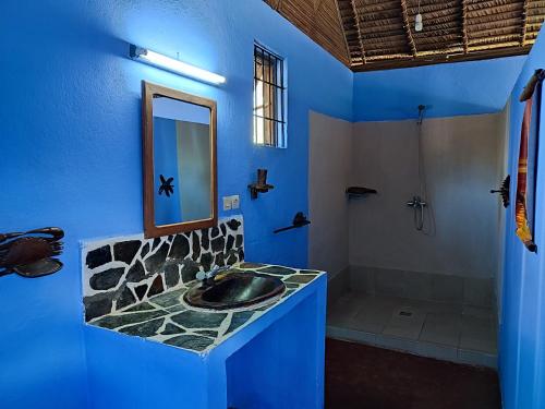 La salle de bains bleue est pourvue d'un lavabo et d'une douche. dans l'établissement Auberge Le Lagon, à Nosy Be