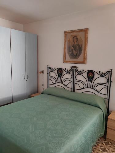 a bedroom with a green bed with a picture on the wall at Villaglauca in Maratea
