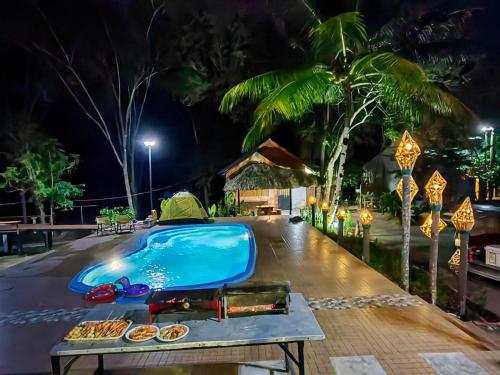 a swimming pool at night with food on a table at Phumaihom Resort in Hat Yai