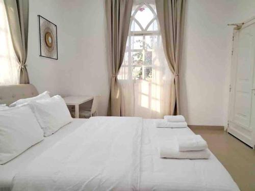 1 cama blanca en un dormitorio con ventana en Villa 9 Palms Beach en Ras al-Jaima