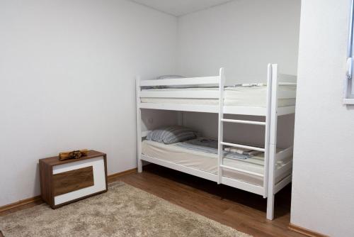 Cette chambre dispose de lits superposés blancs et d'une table. dans l'établissement Villa Lotta & Nolla, à Mostar