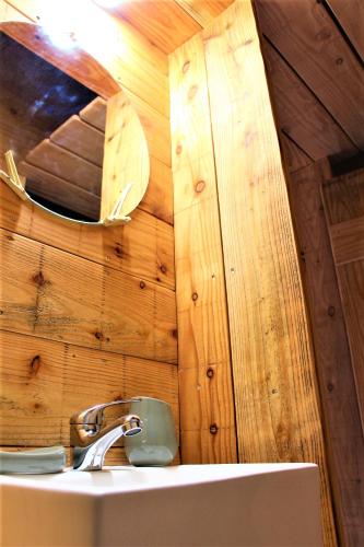 une salle de bain avec un lavabo et un miroir sur un mur dans l'établissement Le Moulin du Luech, à Peyremale