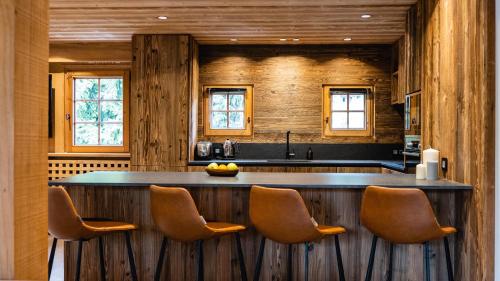 a kitchen with a bar with chairs in it at Chalets de l'Alpaga in Megève