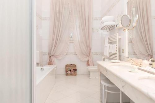 a white bathroom with a tub and a toilet and a sink at Duchessa Isabella Collection by Uappala Hotels in Ferrara
