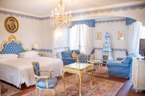 a bedroom with a bed and chairs and a chandelier at Hotel & SPA Duchessa Isabella Collection by GSA Hotels in Ferrara