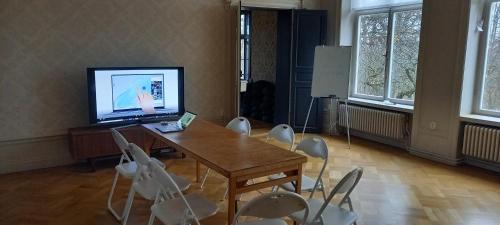 a room with a table and chairs and a television at Arbottna Herrgård AB in Muskö