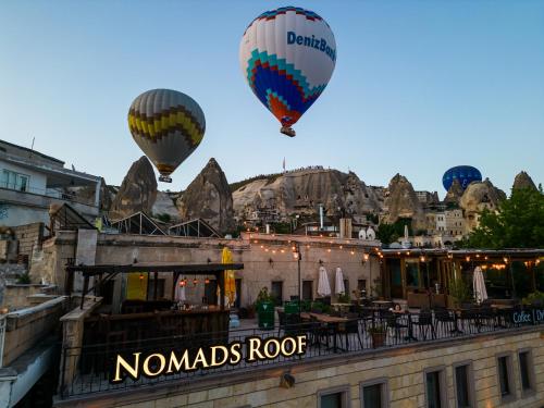 Deux montgolfières survolent un bâtiment dans l'établissement Nomads Cave Hotel & Rooftop, à Gorëme