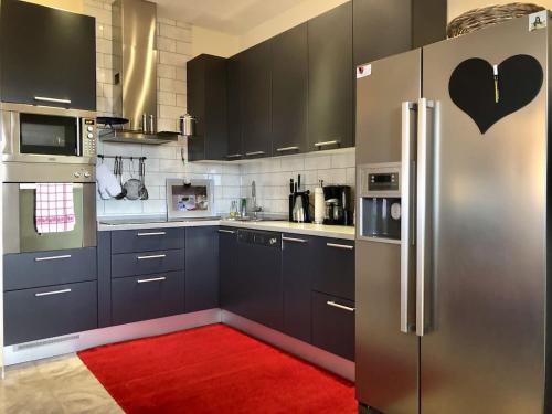 a kitchen with a stainless steel refrigerator and a red rug at Wohnung mit Meerblick Romy in Preko