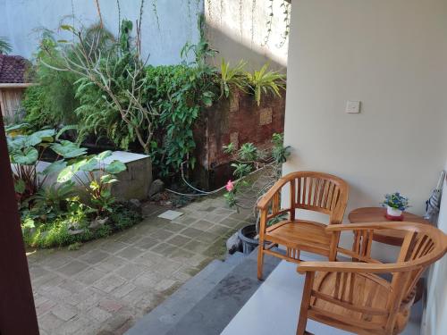 een patio met een tafel, een stoel en een kat bij Kubu Di-Kayla's in Sanur