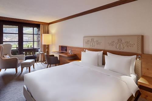a hotel room with a large white bed and a desk at Parkhotel Oberstaufen in Oberstaufen