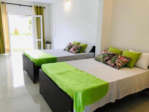 2 camas en una habitación con sábanas verdes en Castile inn, en Puttalam