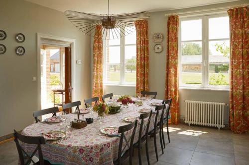 une salle à manger avec une table, des chaises et des fenêtres dans l'établissement La maison d'Hector, à Doudeville