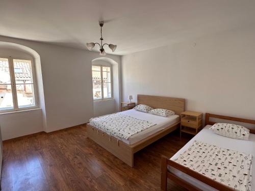 a bedroom with two beds and two windows at UNA apartment in center of Mali Lošinj in Mali Lošinj